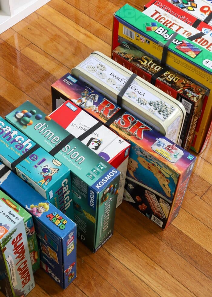 Board games standing on end with large rubber bands holding them shut