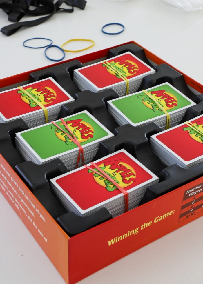Apples to Apples cards bound with rubber bands loaded into box
