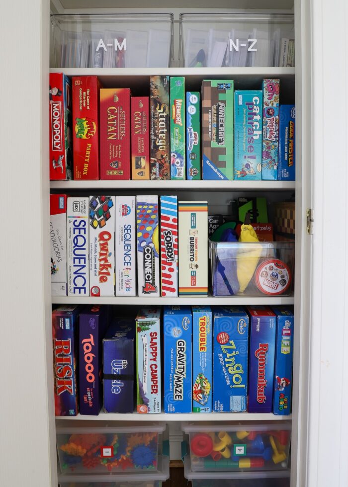 Organized game closet with board games standing on their sides in color order