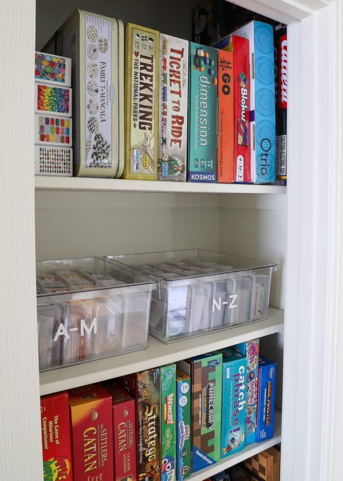 Organized game closet with board games standing on their sides and smaller games inside clear bins