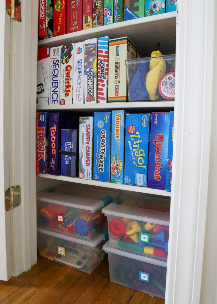 Organized board games standing on their sides with larger games in plastic bins underneath