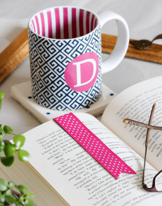 Pink monogram coffee mug next to book