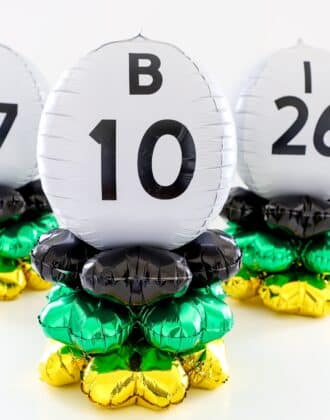Bingo ball table centerpieces made of black, gold, green, and white balloons