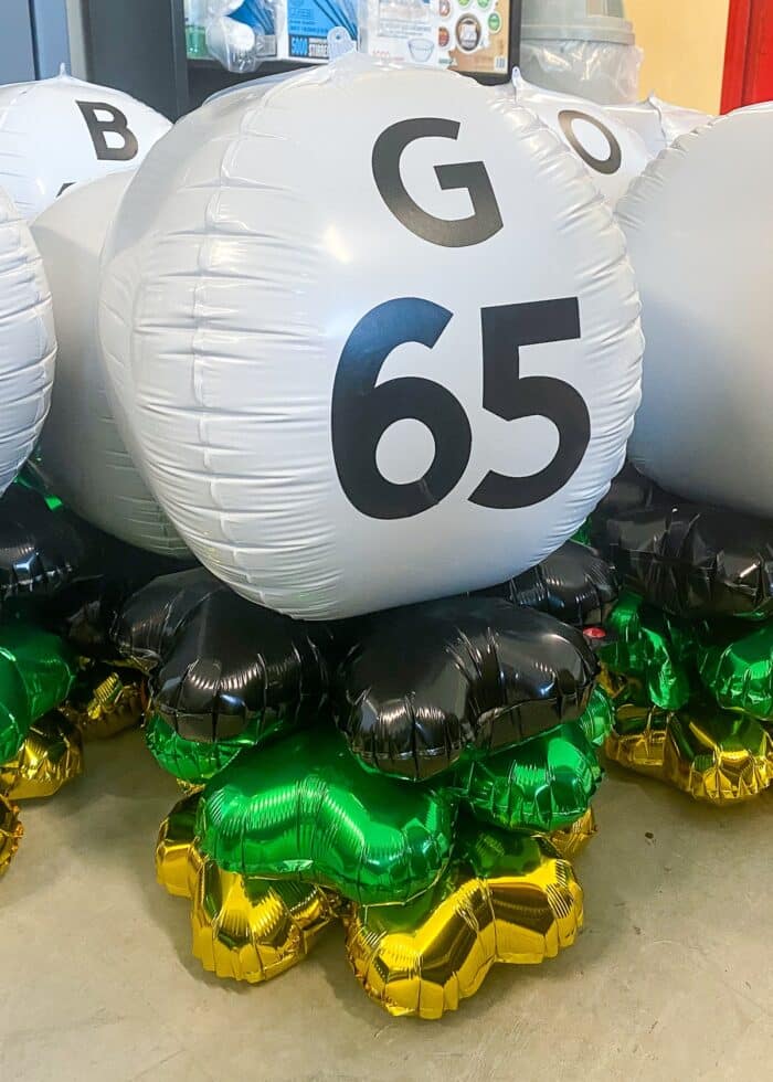 G65 Bingo ball table centerpiece made of black, gold, green, and white balloons