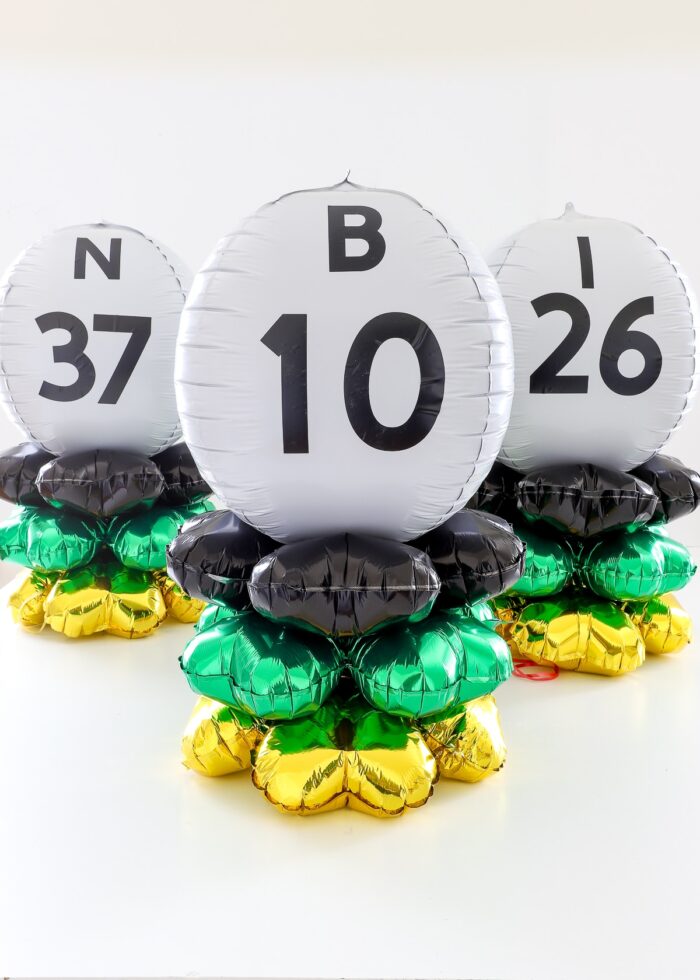 Bingo ball table centerpieces made of black, gold, green, and white balloons
