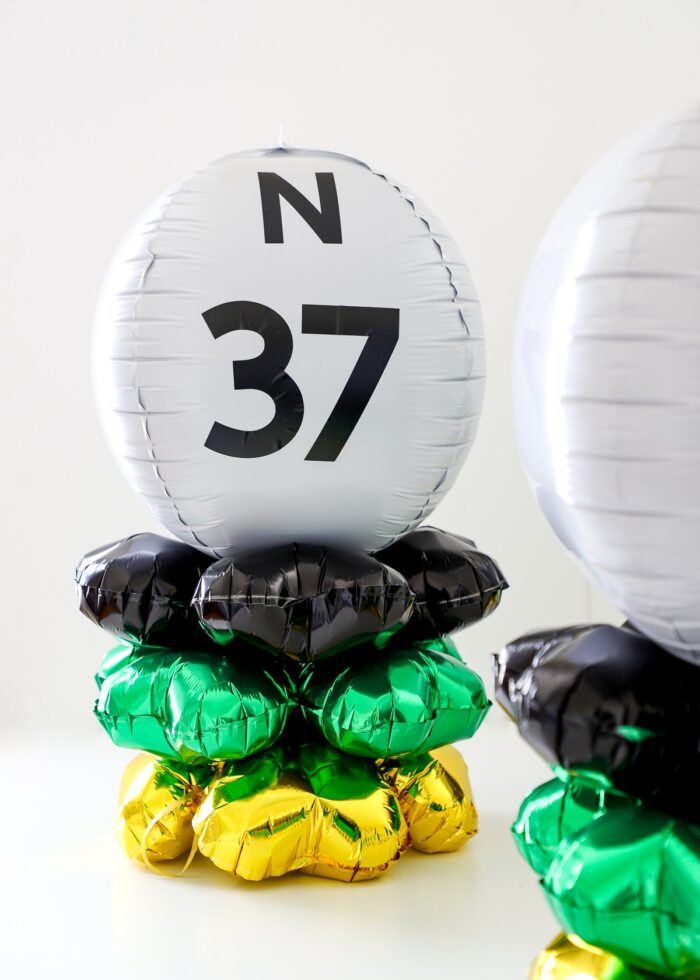 N37 Bingo ball table centerpieces made of black, gold, green, and white balloons