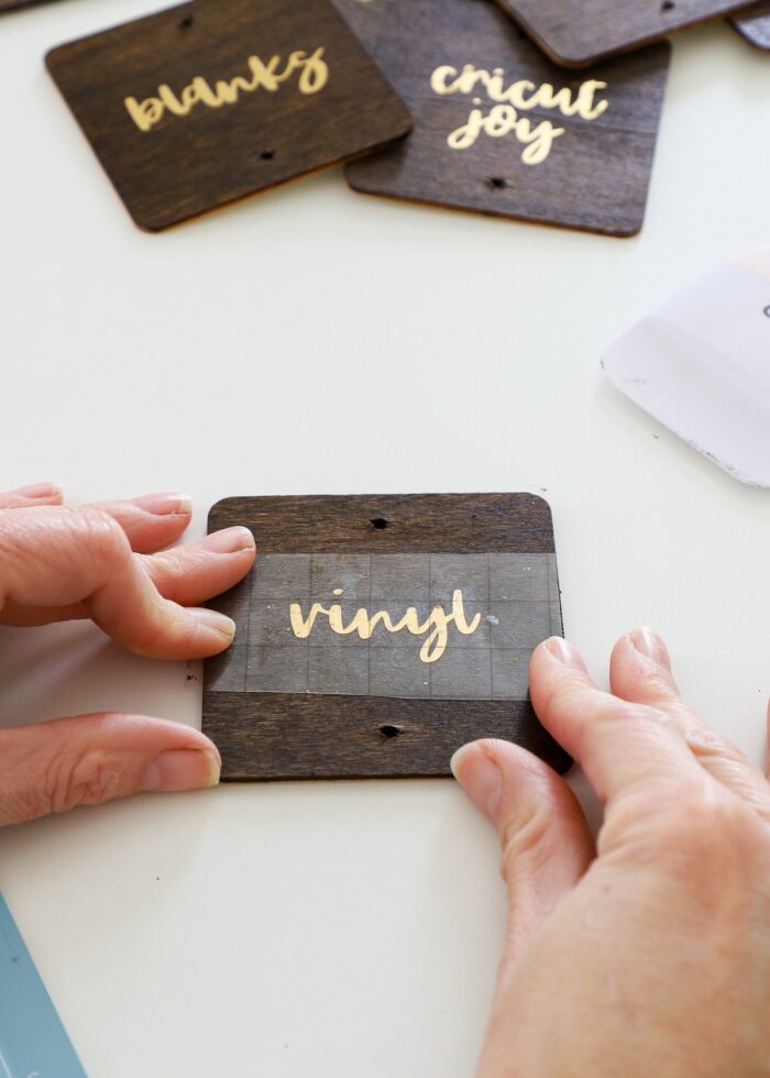 Hands placing gold vinyl text onto stained wood labels