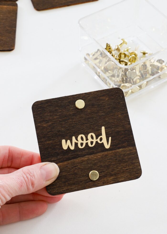 Hand holding wood label with gold foil text in vinyl