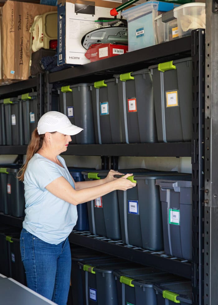 Megan in a light blue shirt putting a storage bin on a shelf