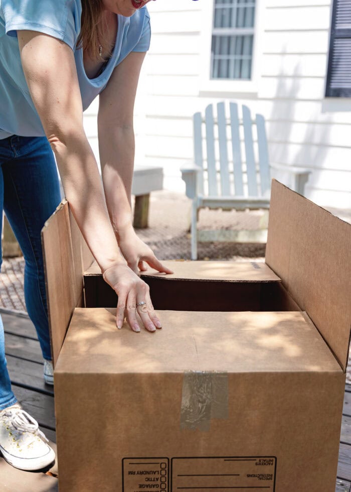 Megan in a light blue shirt packing a moving box