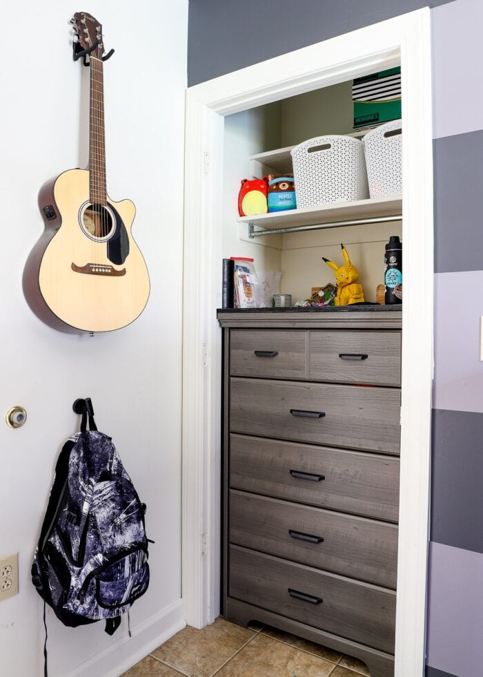 Tall grey dresser inside a skinny bedroom closet