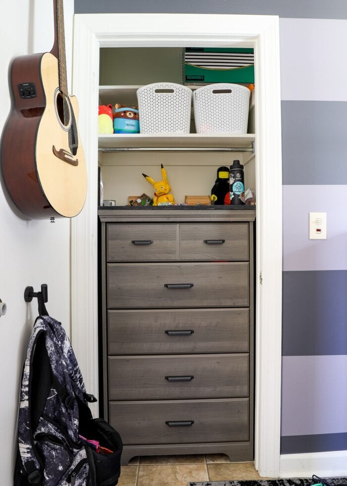 Tall grey dresser inside a skinny bedroom closet