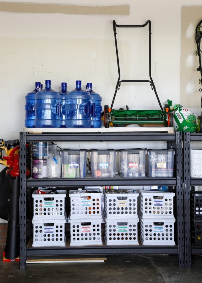 Storage shelves in a garage holding clear bins and crates