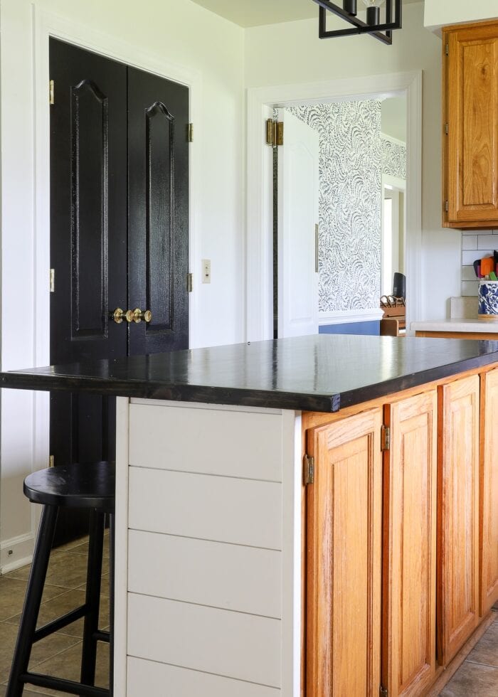 Glossy black pantry doors in a white and oak kitchen