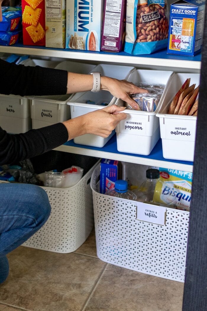 Megan's hands reaching for popcorn inside the organized pantry of this rental kitchen makeover