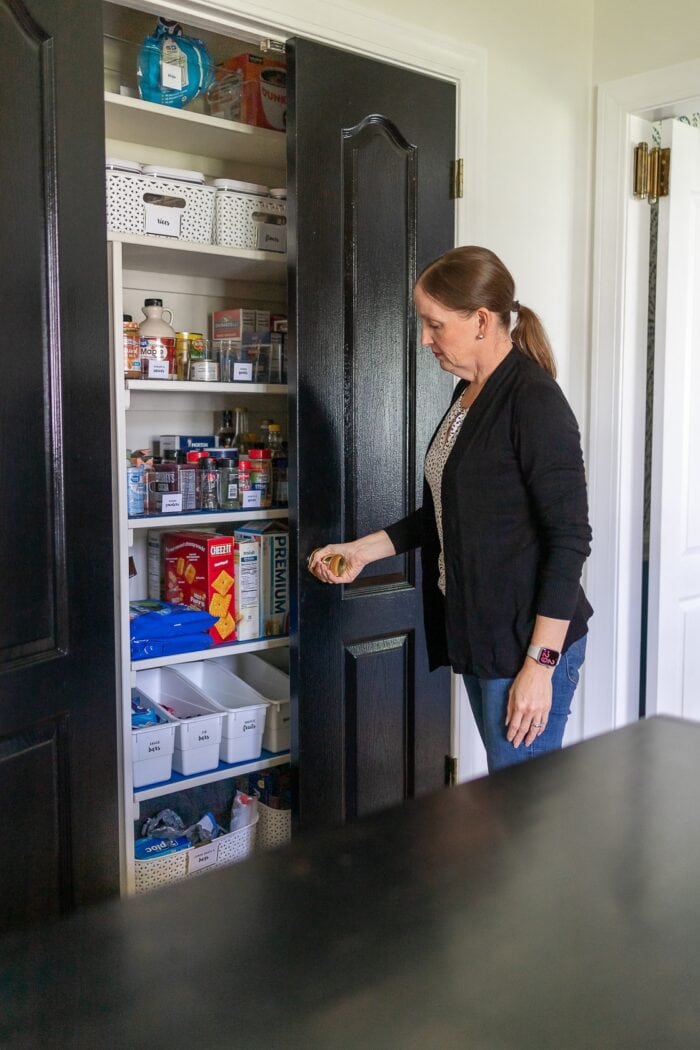 Megan opening the organized pantry of this rental kitchen makeover