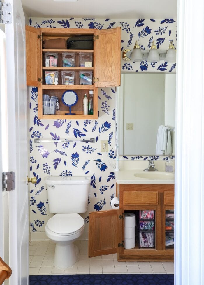 Organized master bathroom cabinets with blue flowered wall decals on the wall