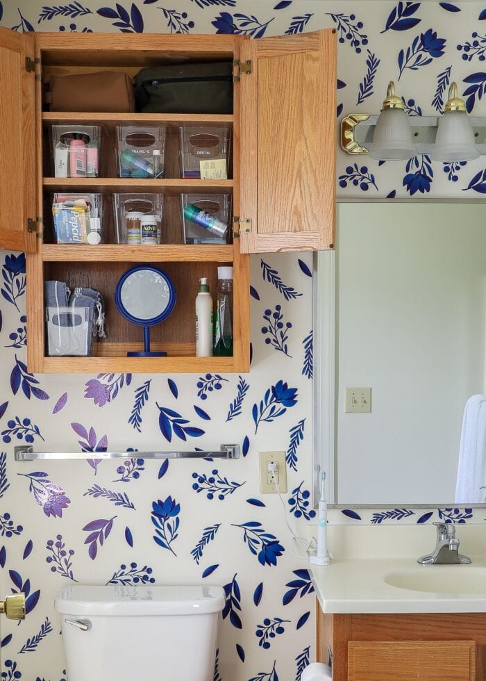 Oak upper bathroom, cabinet with clear storage bins inside.