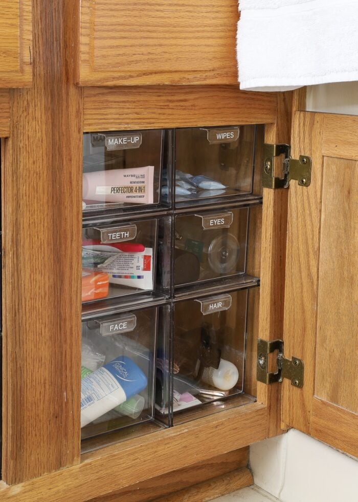 Oak bathroom cabinet under the sink filled with clear acrylic drawers