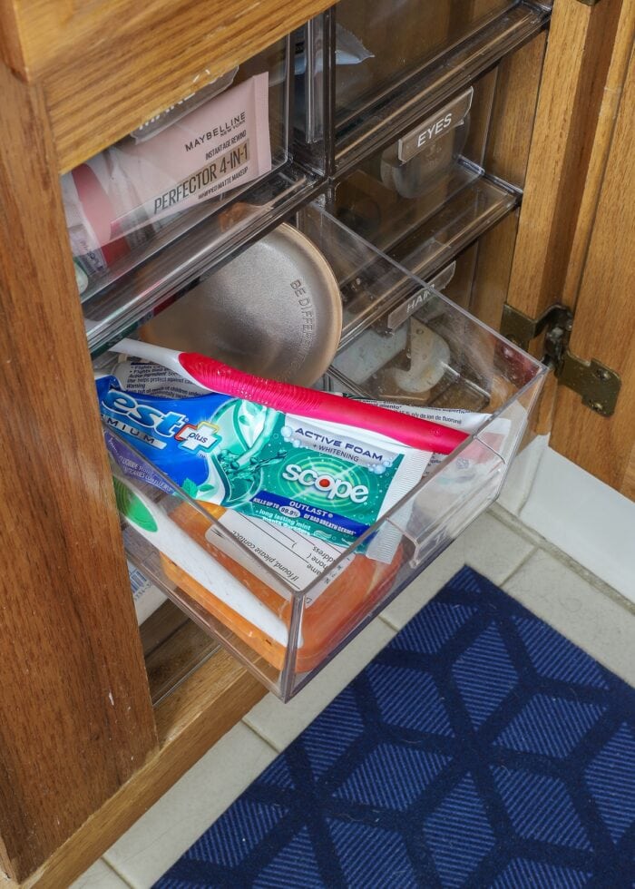 Clear acrylic drawers holding hygiene supplies under a bathroom sink