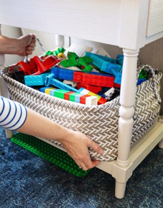 Hands placing a basket of Duplo blocks under a side table