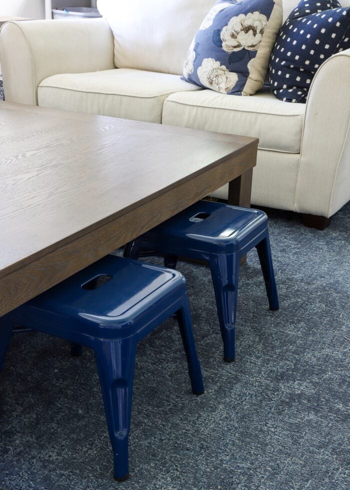 Blue metal kids' stools underneath a large coffee table in a living room