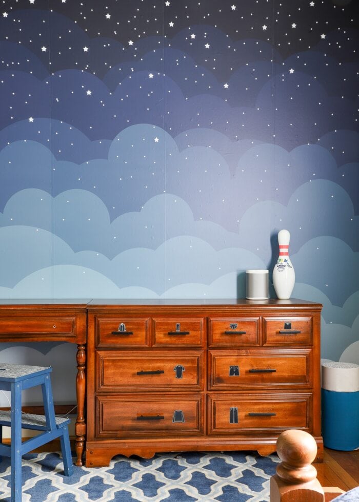 A wallpaper mural of the night sky on a boys' shared bedroom wall