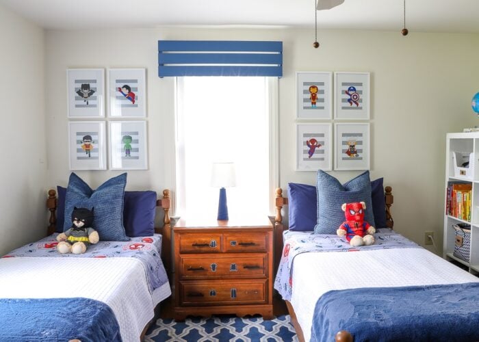 A boys' shared bedroom with twin beds done up in hues of blue and a subtle super hero theme