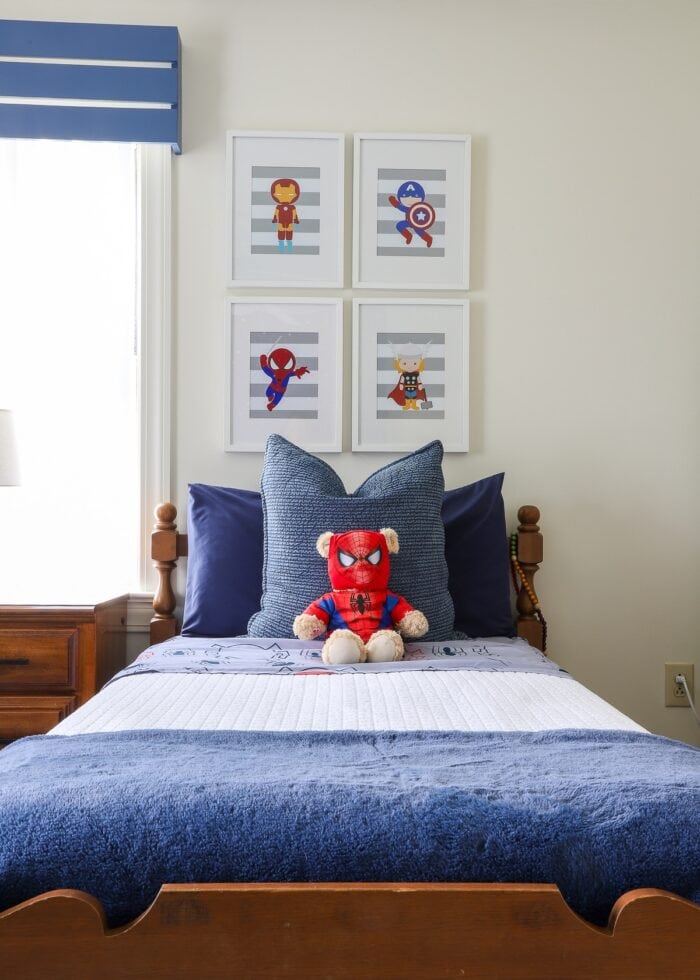 A boys' twin bed with super hero artwork hung above
