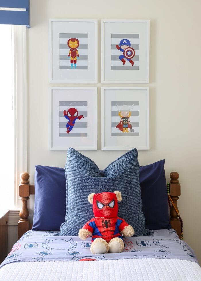 A boys' twin bed with super hero artwork hung above
