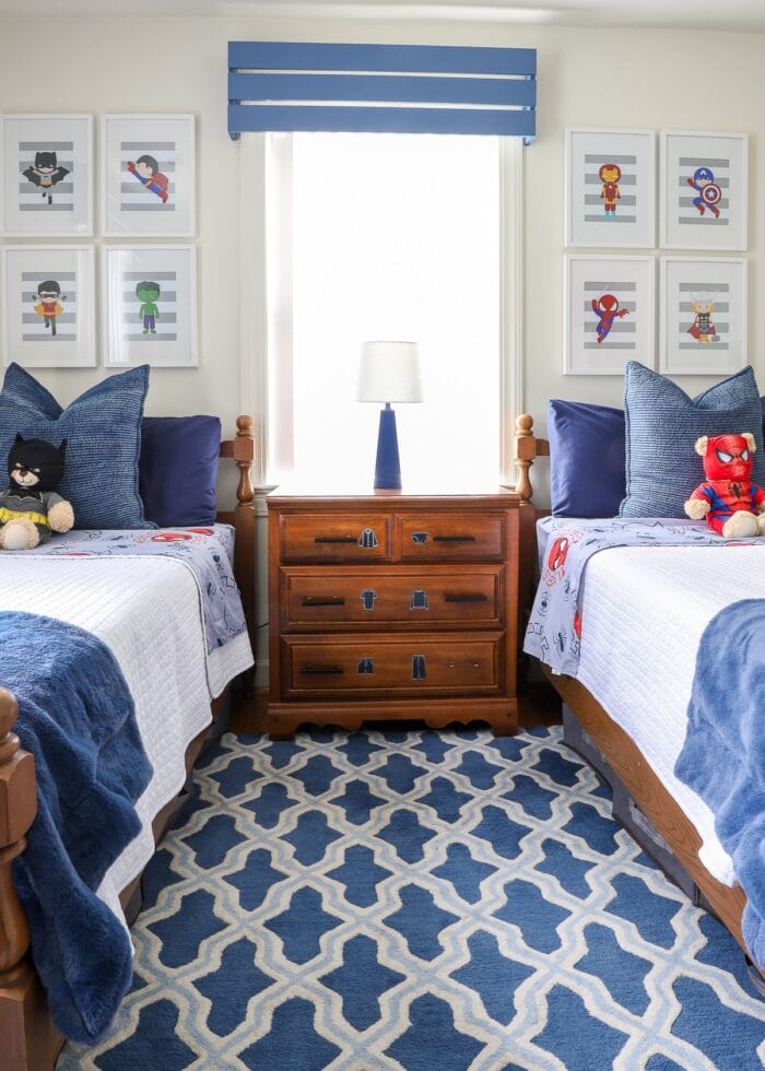 A small dresser in between two twin beds on top of a blue patterned rug