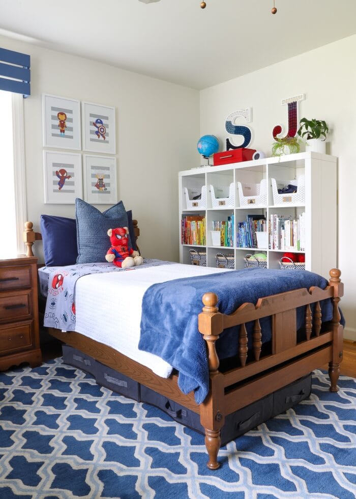 A twin bed next to a white IKEA Kallax shelf holding kids' books