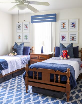 A boys' shared bedroom with twin beds done up in hues of blue and a subtle super hero theme