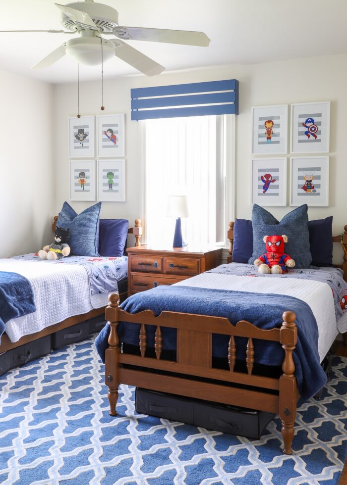 A boys' shared bedroom with twin beds done up in hues of blue and a subtle super hero theme