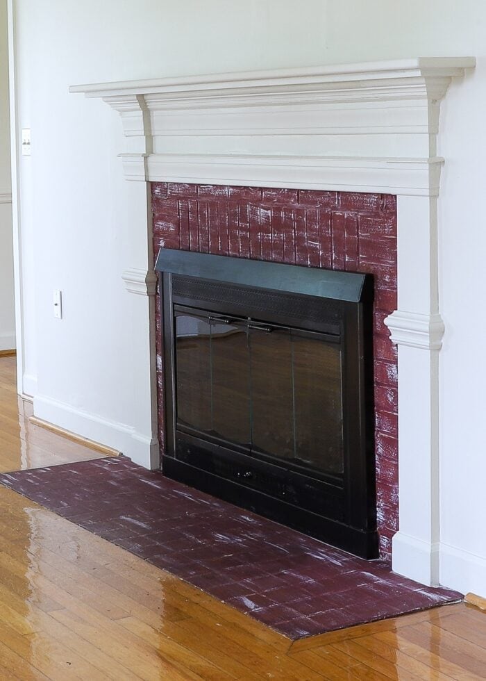 A brick fireplace painted with maroon paint