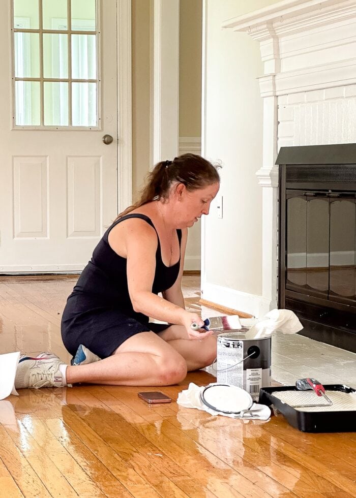 Megan from The Homes I Have Made painting a hearth with white paint