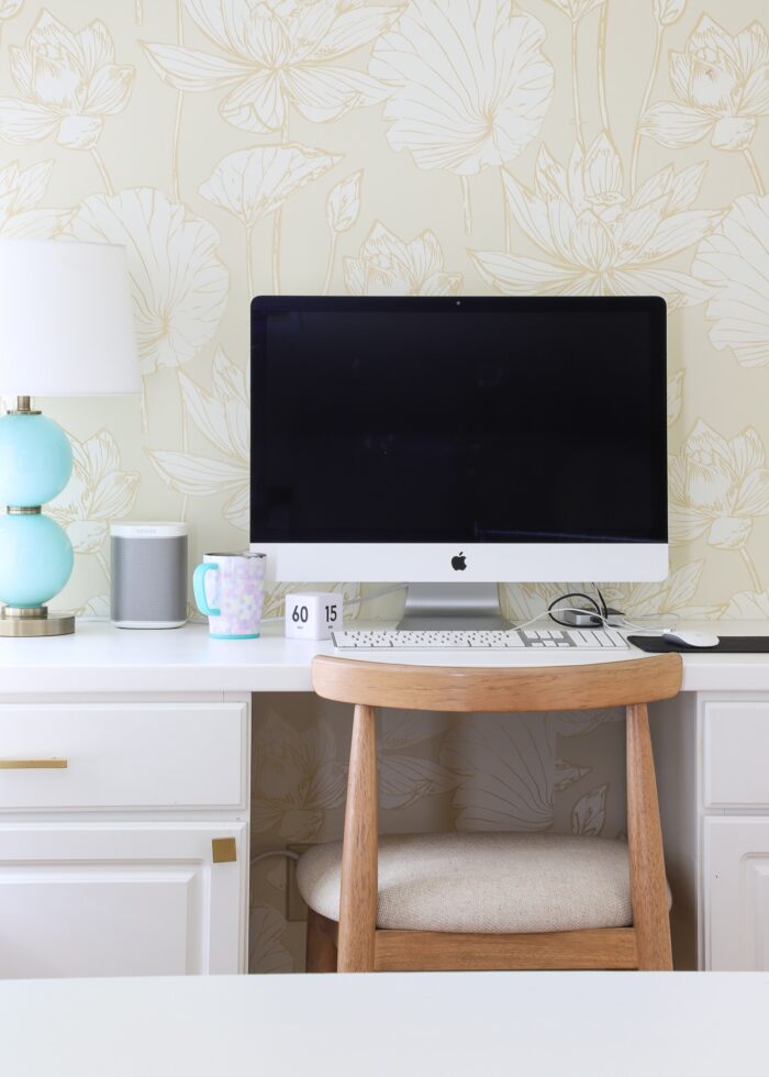 Computer station setup on a white countertop with a wood stool and turquoise lamp