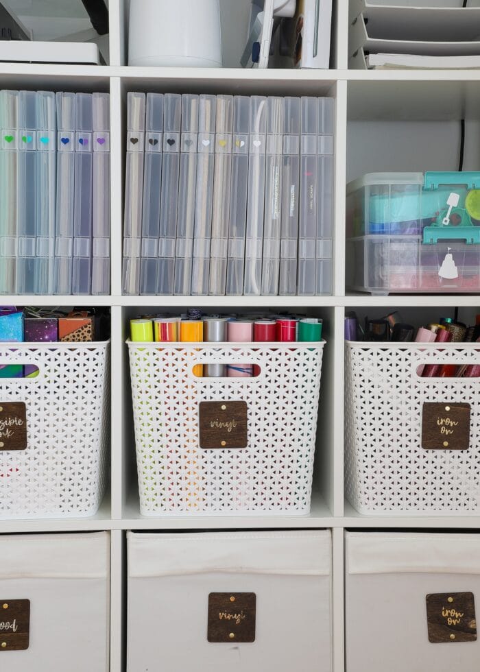 A variety of white baskets and clear storage cases holding craft supplies on a white shelf