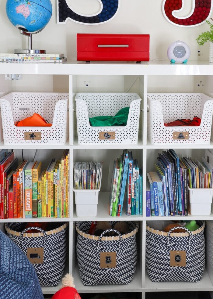 IKEA Kallax shelf holding books organized by color and accessorized with baskets