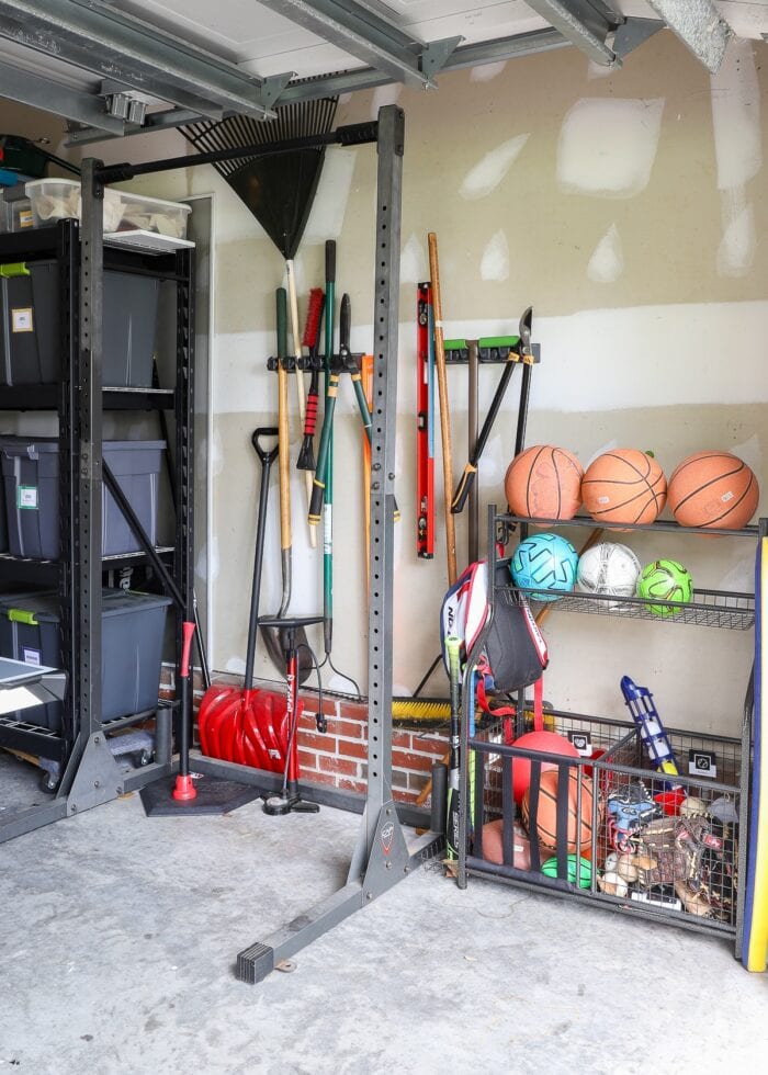 A free-standing pull-up bar alongside organized garden tools and sports equipment in a garage