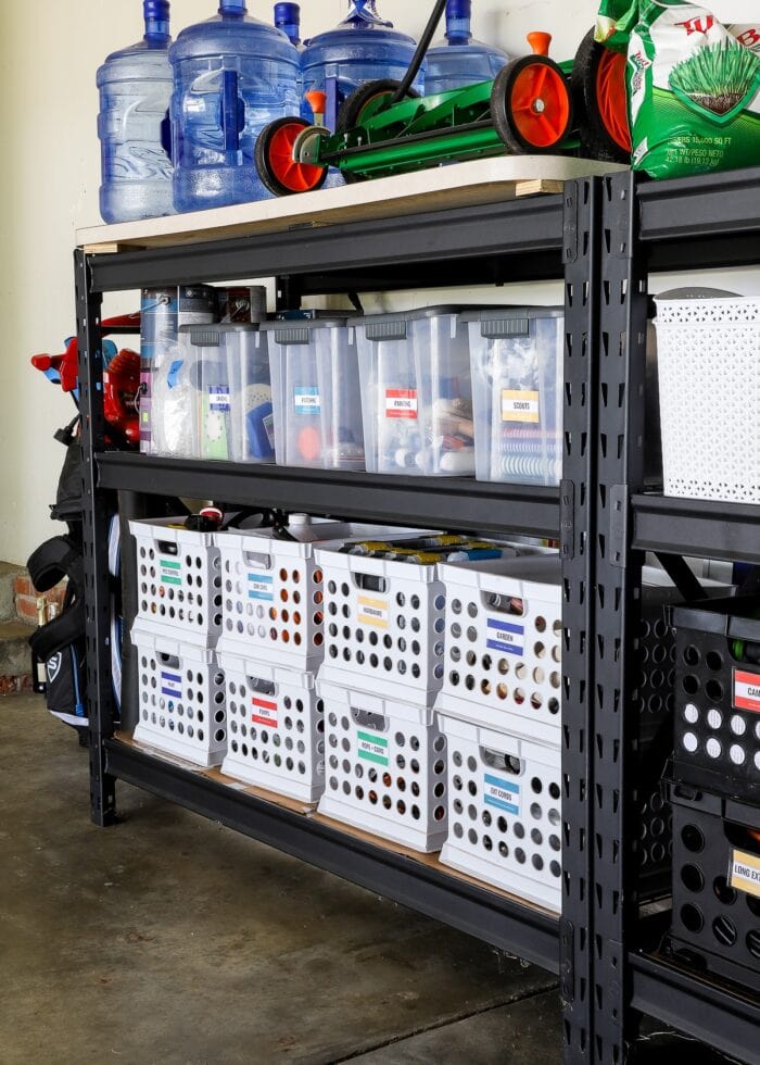 Garage shelves holding a variety of items stored in white crates and plastic bins.