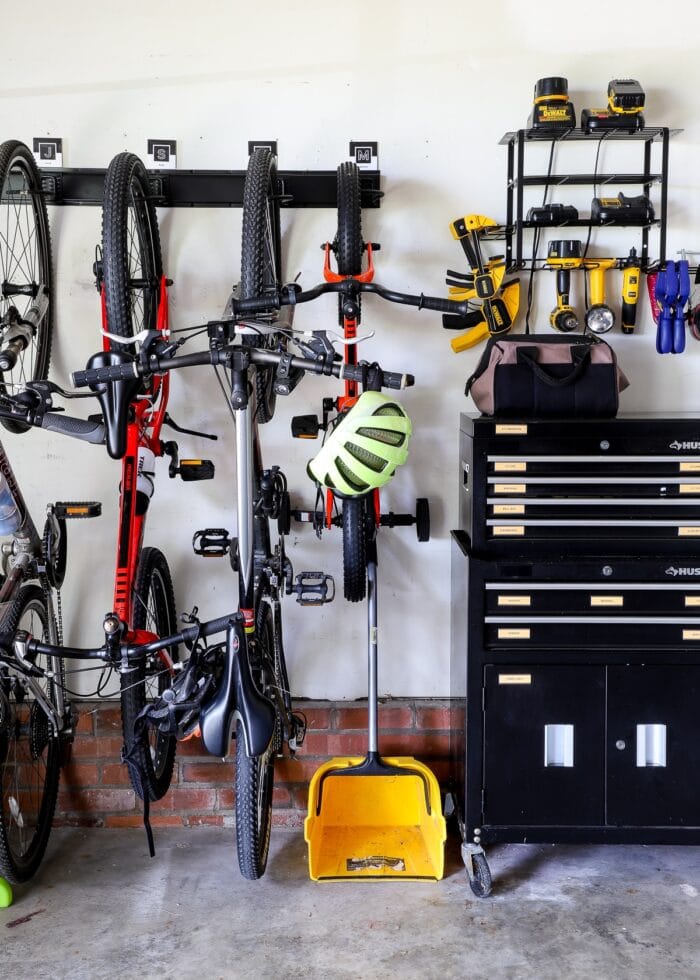 Bikes stored on a garage wall alongside a small rolling tool chest