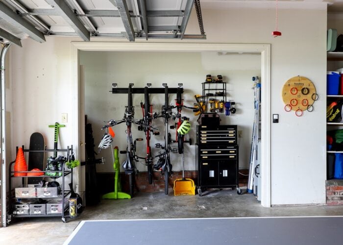 A nook inside an organized garage holds mounted bikes and a rolling tool chest with mounted tool organization above.