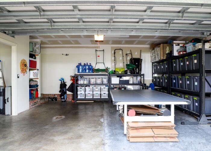 A wide shot of our organized garage featuring tall storage shelves with bins, a ping pong table, lawn equipment storage, and a shelf full of beach gear.