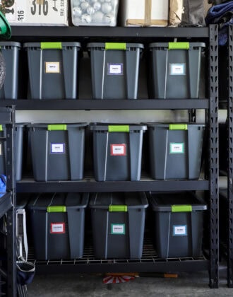 Matching storage totes with colorful labels on tall garage shelves