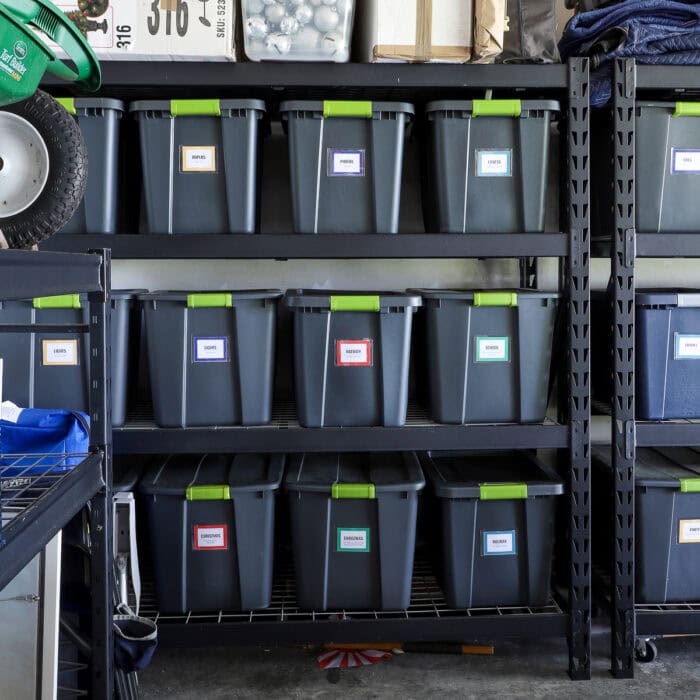 Matching storage totes with colorful labels on tall garage shelves