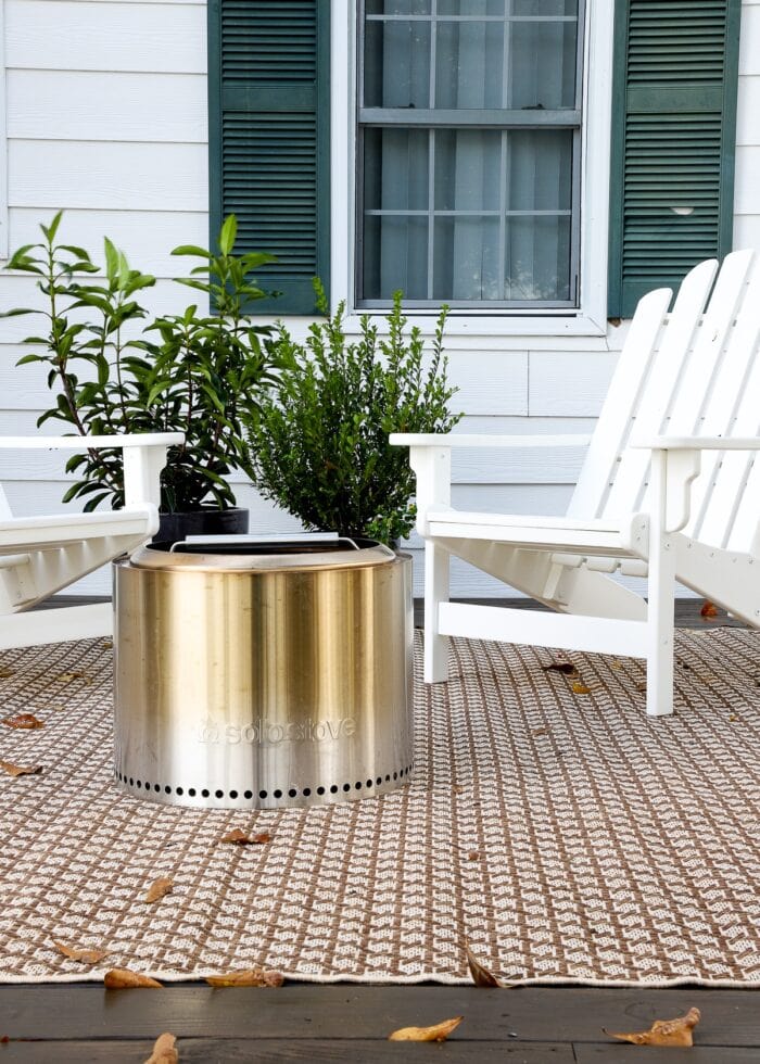 Two white chairs on a brown rug with a solo stove and plants