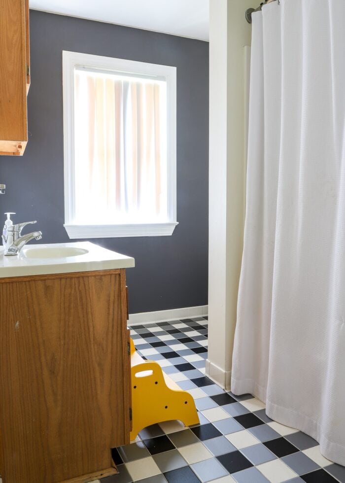 Kids bathroom with grey walls, black and white checkered floor, and yellow accents