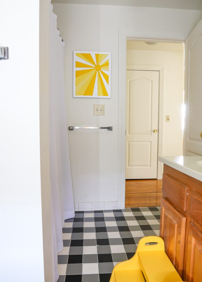 Kids bathroom with grey walls, black and white checkered floor, and yellow accents