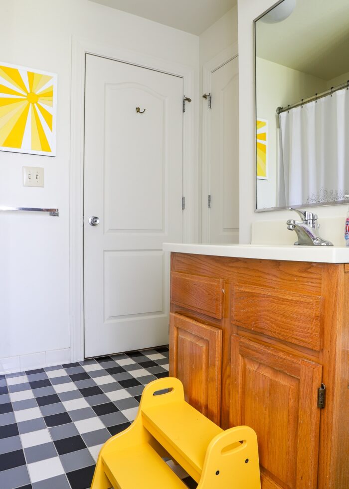 Kids bathroom with grey walls, black and white checkered floor, and yellow accents